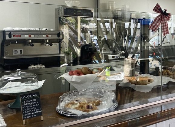 The counter at Bagelicious Café: espresso machine behind the glass, bagels and pastries in front