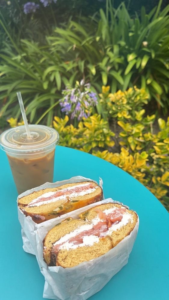 Lox and cream cheese bagel halves and an iced coffee on a turquoise outdoor table