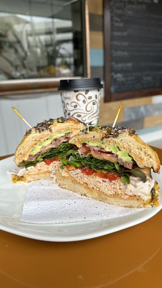 Tall turkey and avocado sandwich on an everything bagel, cut in half